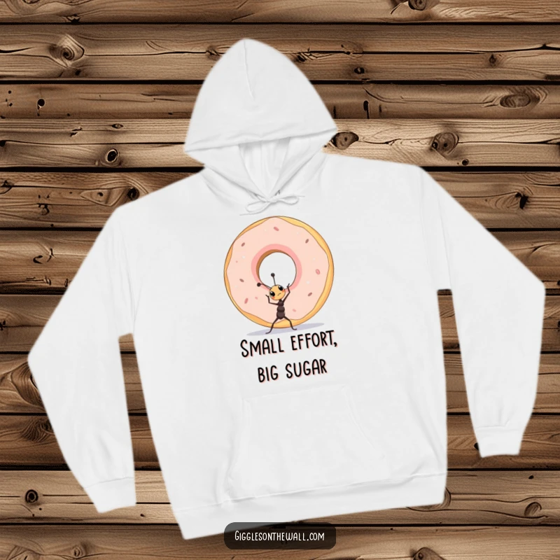 Funny tiny ant lifting a colossal donut, depicted on a warm and cozy hoodie, celebrating perseverance.