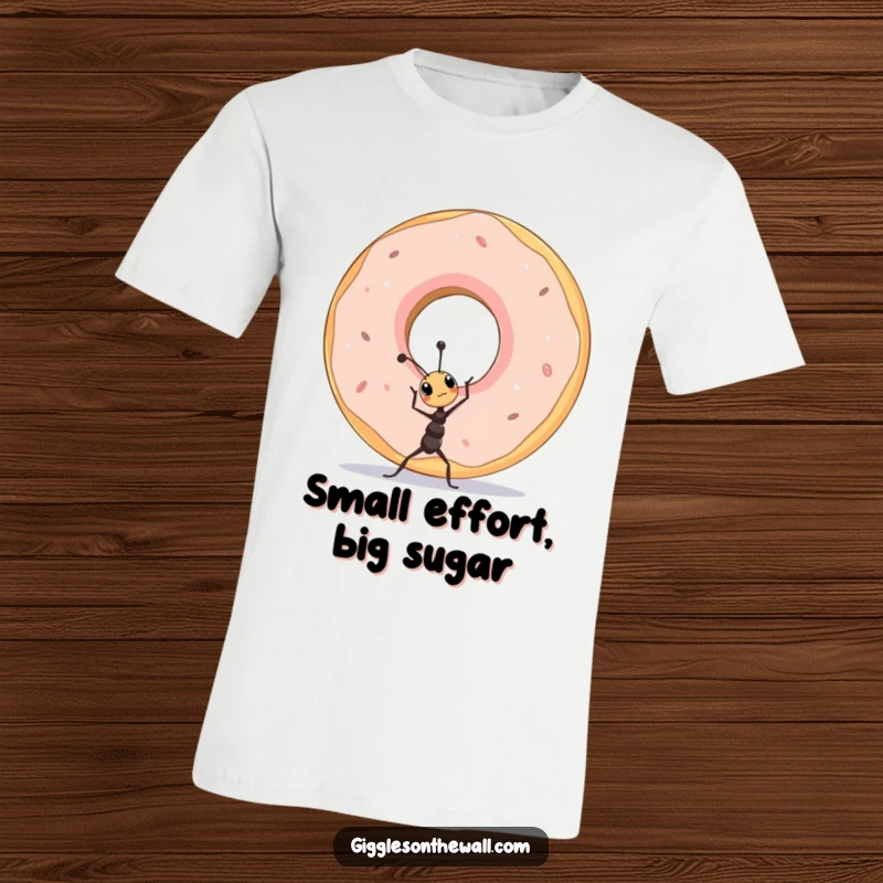 Funny tiny ant character straining to lift a comically oversized donut, printed on a graphic t-shirt.